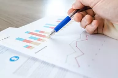 Hand holding pen over bar graph